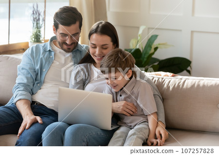 Happy young parents with little son using laptop together Happy young parents with little son using laptop together 107257828