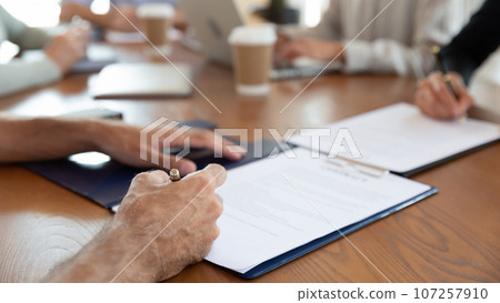 Seated at desk parties putting signature on commercial agreement closeup 107257910