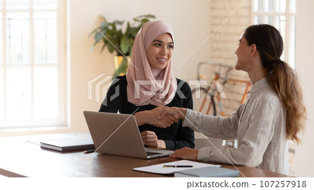 Middle eastern ethnicity and mixed-race businesswomen shaking hands 107257918