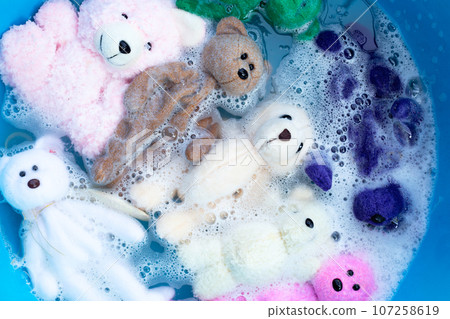 Soak toy teddy bears in laundry detergent water dissolution before washing. Laundry concept, Top view Soak toy teddy bears in laundry detergent water dissolution before washing. Laundry concept, Top view 107258619