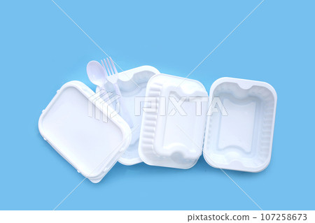 Plastic food boxes with spoon and fork on blue background. Plastic food boxes with spoon and fork on blue background. 107258673