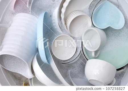 Dishes and bowls in water and bubbles of dishwashing liquid. Kitchen work 107258827