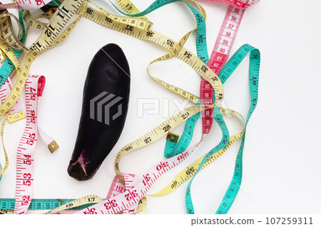 Eggplant with measuring tape on white background. Eggplant with measuring tape on white background. 107259311