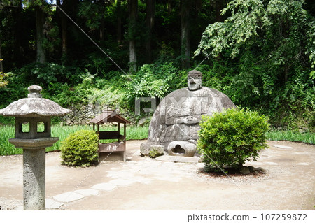 Manji stone Buddha through stone lantern 107259872