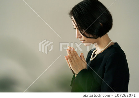 一名婦女在葬禮上雙手合十祈禱 107262071