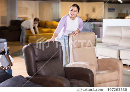 Young woman is looking for a new armchair 107263886