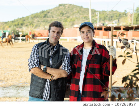 Portrait of a married couple owners of stable against the backdrop of corral for walking horses Portrait of a married couple owners of stable against the backdrop of corral for walking horses 107263957