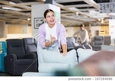 Female furniture salesperson showing armchairs for sale in furniture showroom Female furniture salesperson showing armchairs for sale in furniture showroom 107264090