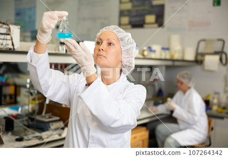 Efficient female lab technician working with reagents in test tubes during chemical experiment Efficient female lab technician working with reagents in test tubes during chemical experiment 107264342