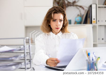 Portrait of tired woman bookkeeper sitting at table Portrait of tired woman bookkeeper sitting at table 107264359