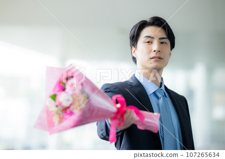 一個穿著西裝的男人拿著一束鮮花 107265634