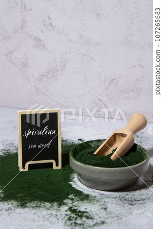 Blue-green algae Chlorella and spirulina powder in bowl with blackboard text SPIRULINA SEA WEED. Super powder. Natural supplement of algae. Detox superfood drink cocktail. Food supplement source of 107265683