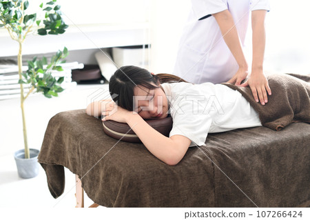Young Asian woman receiving a massage (manipulative treatment) in bed Young Asian woman receiving a massage (manipulative treatment) in bed 107266424