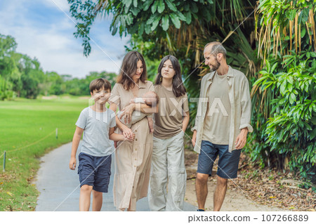 Happy couple in their 40s, surrounded by adult children, cradle a newborn in a sunlit park. Love, family, and generations in harmony 107266889