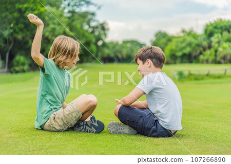 Two young boys share laughter and adventures in the sunlit park, cherishing the bonds of friendship and carefree moments 107266890