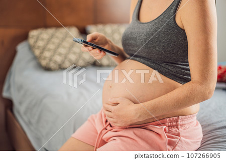 Mobile pregnancy online maternity application. Pregnant mother using phone. Pregnancy, medicine, pharmaceutics, health care and people concept 107266905