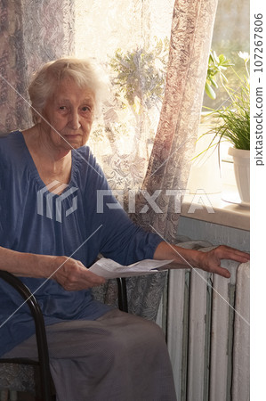 Woman holding cash in front of heating radiator. Payment for heating in winter. Selective focus. 107267806