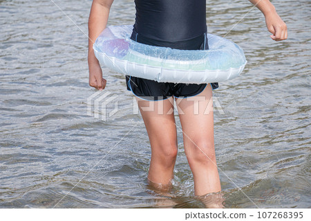 Image of a girl playing in the water with a float and designated swimsuit 107268395
