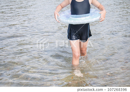 Image of a girl playing in the water with a float and designated swimsuit 107268396