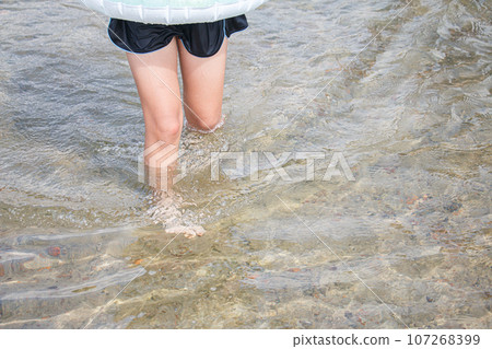 Image of a girl playing in the water with a float and designated swimsuit 107268399