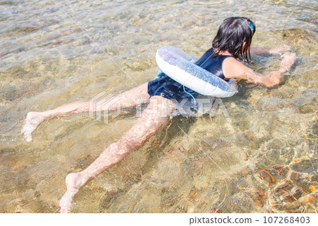 Image of a girl playing in the water with a float and designated swimsuit 107268403