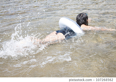 Image of a girl playing in the water with a float and designated swimsuit Image of a girl playing in the water with a float and designated swimsuit 107268562