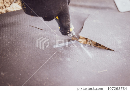 A man cuts a black agricultural fiber along the label A man cuts a black agricultural fiber along the label 107268784