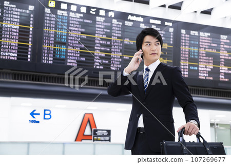 Young businessman on a business trip from the airport while looking at his smartphone 107269677