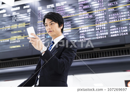 Young businessman on a business trip from the airport while looking at his smartphone Young businessman on a business trip from the airport while looking at his smartphone 107269697
