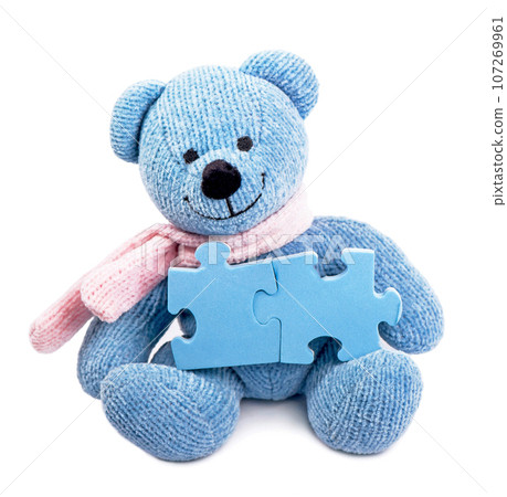 A toy bear knitted from blue threads holds puzzles suitable for writing text, advertising 107269961