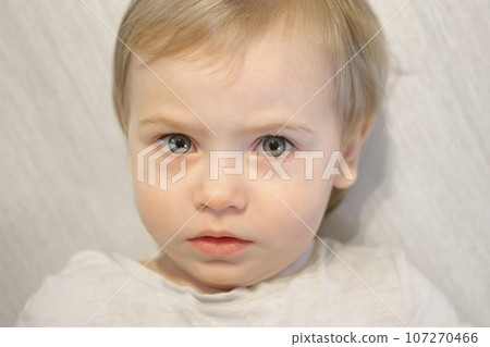 Little Girl looking intently to the Camera. Her gaze is curious, intent. Eyes wide open. Staring Look. Close Up of Baby Child Face on Light Background. Kid Emotion. Facial Expression. 1 Years Old. 107270466