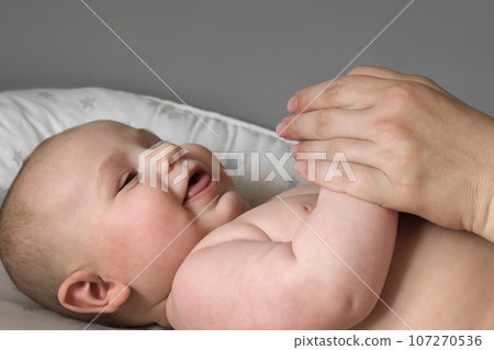 Mother Giving Massage To Little Child. Closeup. Mom Gives massage To Infant Baby. Prevention of Tremor. Female Hands Gently Massaging To Newborn Naked Body. Smears with Cream, Body care concept. Mother Giving Massage To Little Child. Closeup. Mom Gives massage To Infant Baby. Prevention of Tremor. Female Hands Gently Massaging To Newborn Naked Body. Smears with Cream, Body care concept. 107270536