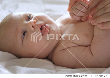 Mother doing Massage to Baby at Home, Playing with Child. Light Background. Infant Baby Massage. Mom makes Massage for Newborn, Apply Oil. Early Age Children Development. Authentic Candid Lifestyle 107270573