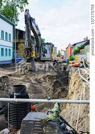 Street reconstruction view, deep trench, dewatering system, new and old pipes, excavator 107270708