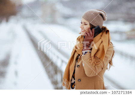 happy elegant woman in brown hat and scarf talking on phone 107271384
