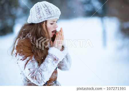 unhappy elegant female warming cold hands with breath unhappy elegant female warming cold hands with breath 107271391