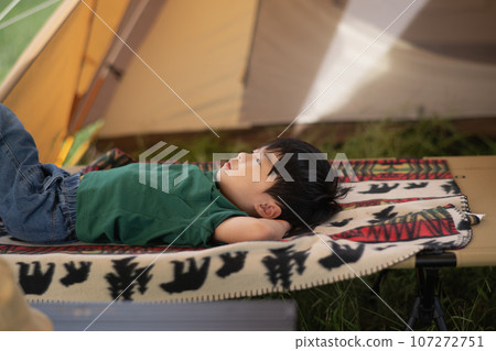 A boy lying on a camp cot A boy lying on a camp cot 107272751