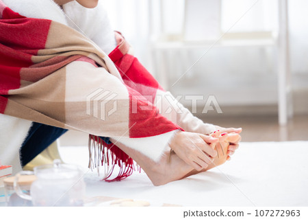 A woman warming her cold feet 107272963