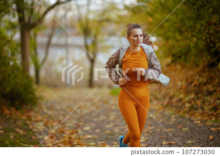 stylish woman in fitness clothes in park running 107273030
