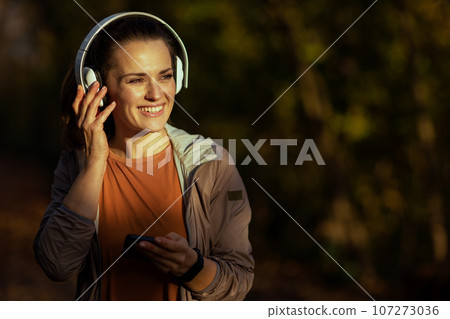 smiling elegant woman in park listening to music 107273036