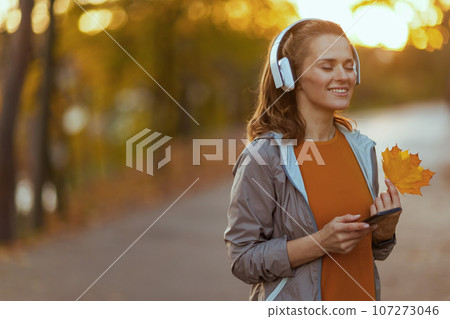 smiling fit 40 years old woman in park listening to music 107273046