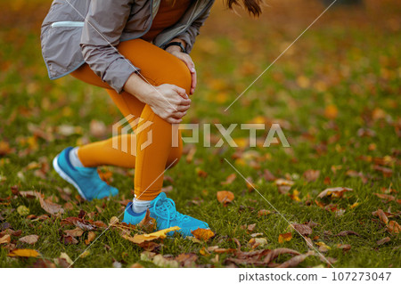 Trendy woman in fitness clothes in park got leg injury 107273047