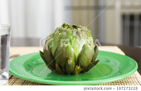 Cooked whole artichoke on a green plate Cooked whole artichoke on a green plate 107273228