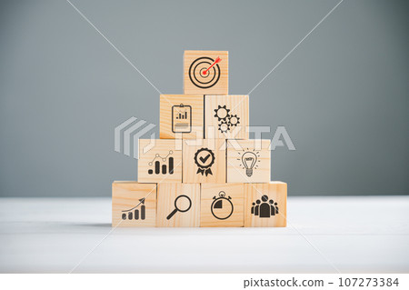 Wooden cube block step on a table with Action Plan, Goal, and Target icons. Success and business target concept. Project management and company strategy for professional growth. 107273384