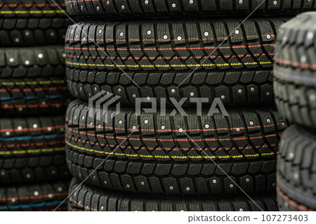 Sale of car tires for sale in the store. Many new winter tires lie horizontally. There is space for text 107273403