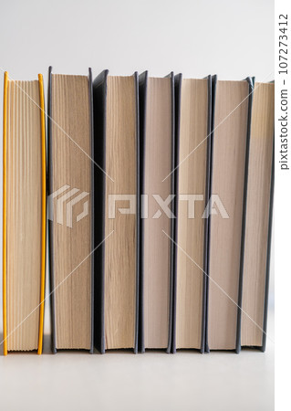 Stack of books on a white background. One book is yellow. Book reading and learning concept. Stack of books on a white background. One book is yellow. Book reading and learning concept. 107273412