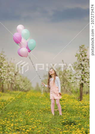 girl with balloons in a young garden 107273474