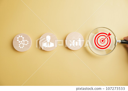 Magnifying glass hones in on target icon, symbolizing fusion of start-up, creative ideas, and innovation. signifies motivation, planning, development, and leadership for customer targeting in business Magnifying glass hones in on target icon, symbolizing fusion of start-up, creative ideas, and innovation. signifies motivation, planning, development, and leadership for customer targeting in business 107273533
