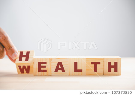 Flip wooden cube Wealth to Health. Health and wealth concept on table. Symbolic investment from money to well-being. Wellness healthcare 107273850