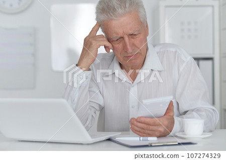 Senior businessman working with his laptop at office Senior businessman working with his laptop at office 107274329